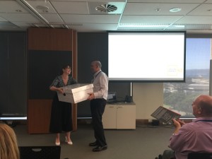 Lydia Hollister-Jones presents the Secretary and Chief Executive of the New Zealand Treasury, Gabriel Makhlouf with the baby box. 
